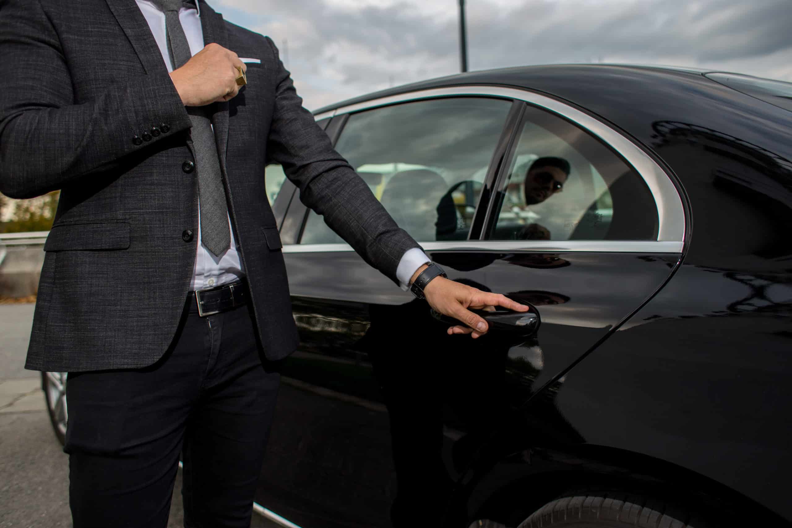 Man opening a black car limousines door